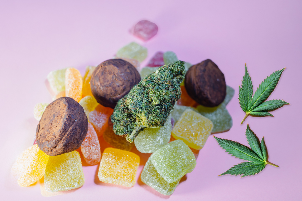 A variety of cannabis-infused gummies and chocolate truffles next to a marijuana bud, highlighting different types of edible marijuana.