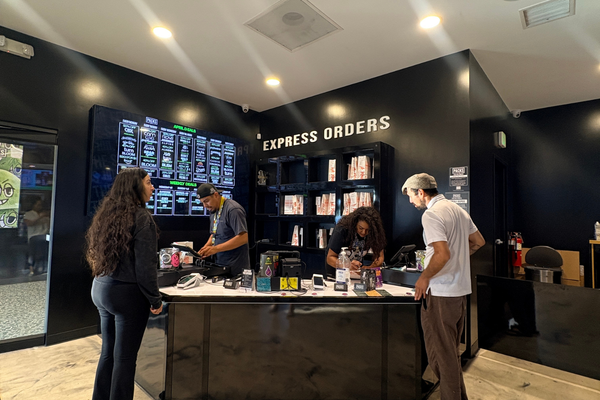 Customers ordering cannabis products at a sleek black dispensary counter in Los Angeles with digital menus and express order signage.