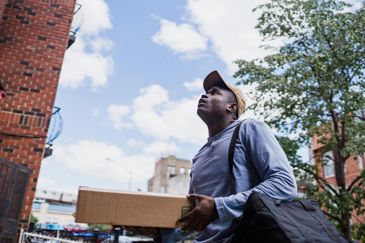A courier navigates an urban residential area to safely drop off a secure package to a verified customer.