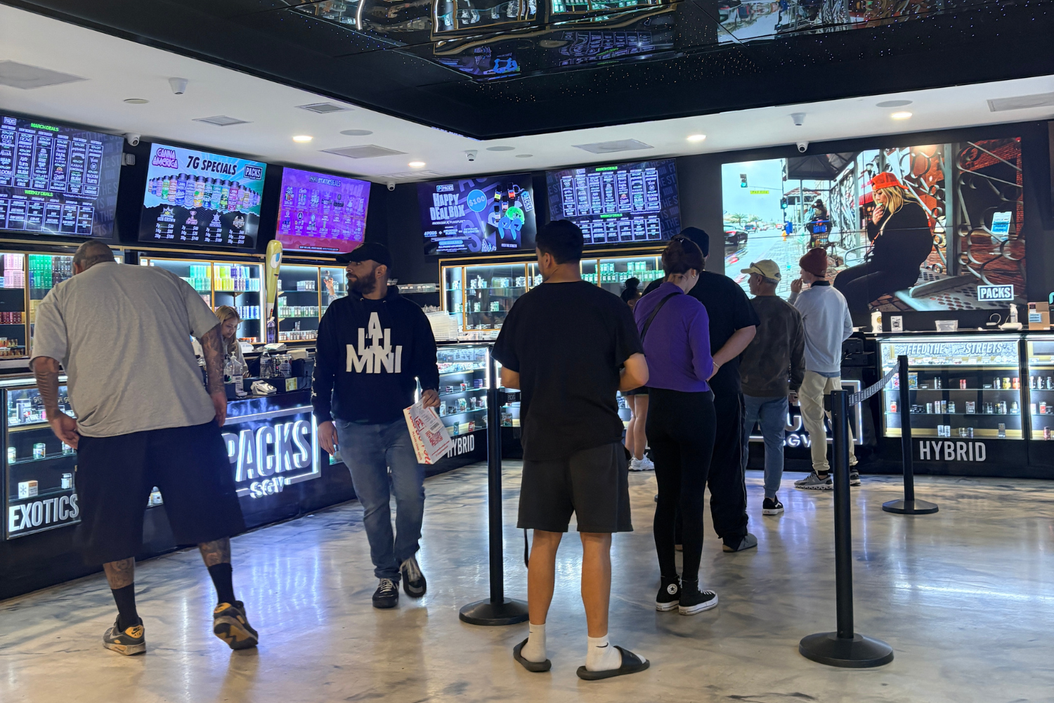 Customers inside Packs Club dispensary in Los Angeles viewing cannabis product displays and digital menu boards.