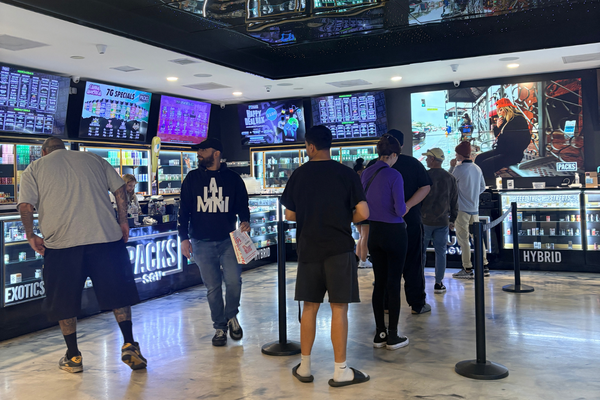 Customers inside Packs Club dispensary in Los Angeles viewing cannabis product displays and digital menu boards.