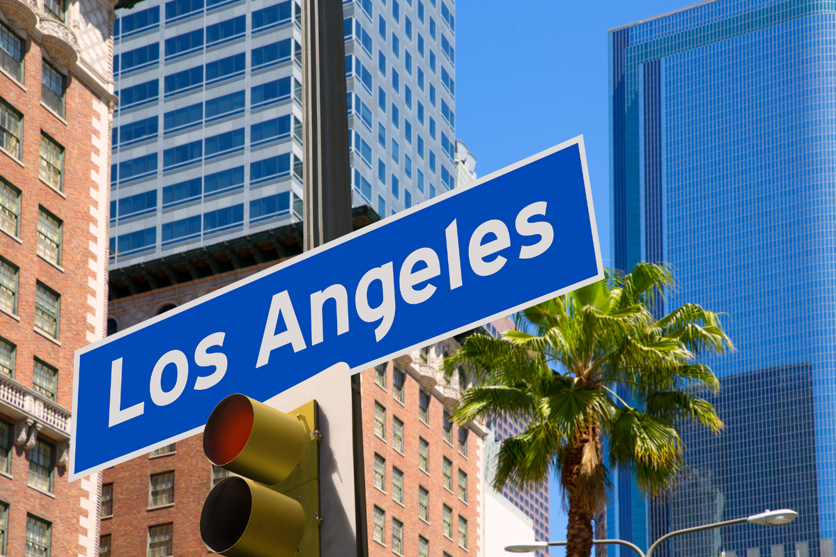 Los Angeles street sign with downtown skyline, representing a typical location where tourists and locals prepare what to bring before visiting a Los Angeles weed dispensary.
