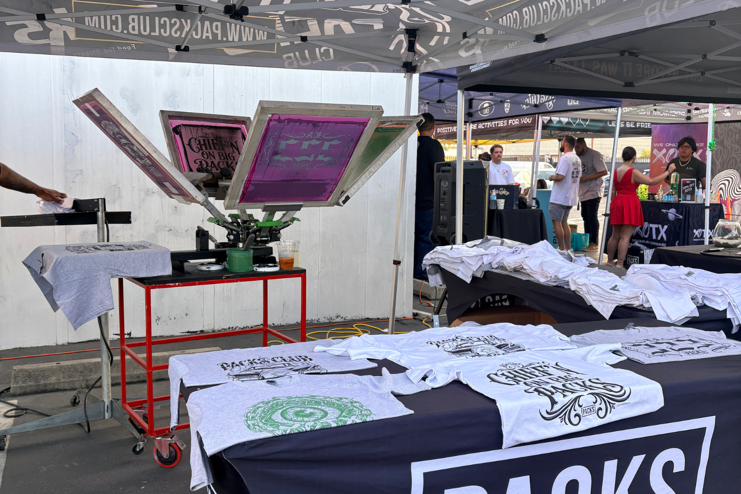 PACKS Club booth with branded apparel and merchandise displayed on tables.