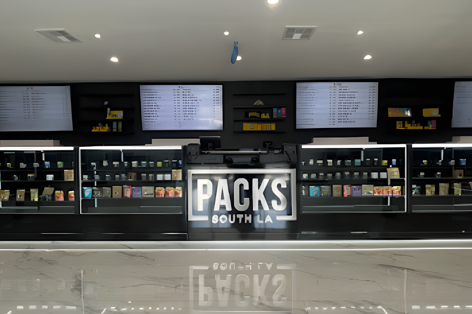 Packs South LA storefront with digital menus above shelves stocked with products and a marble counter in the foreground.