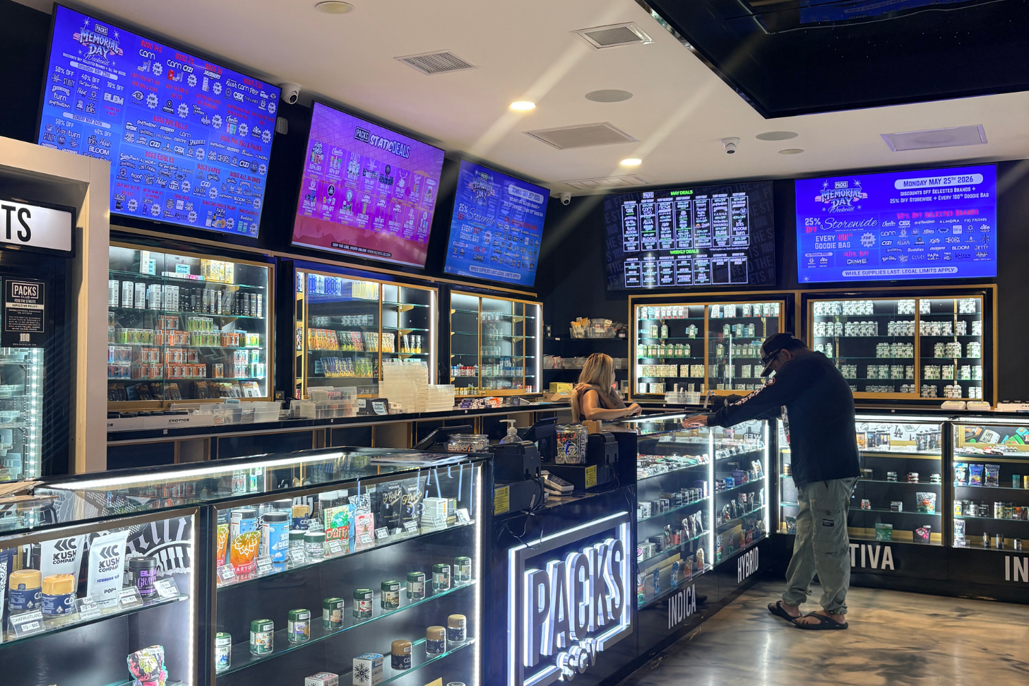 Customer viewing cannabis products and Packs SGV deals on digital menus inside PACKS Club El Monte dispensary.