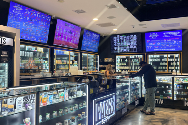 Customer viewing cannabis products and Packs SGV deals on digital menus inside PACKS Club El Monte dispensary.