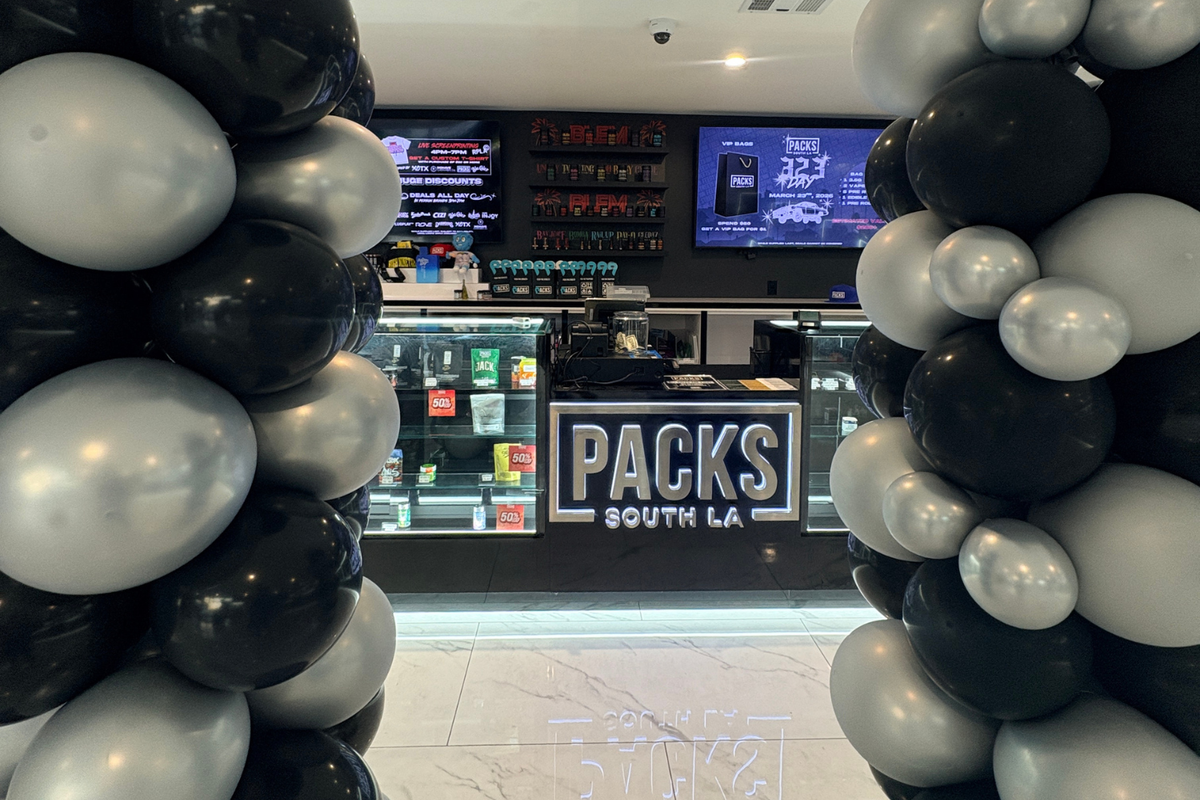 PACKS South LA dispensary counter with product displays, digital menus, and black and silver balloons.