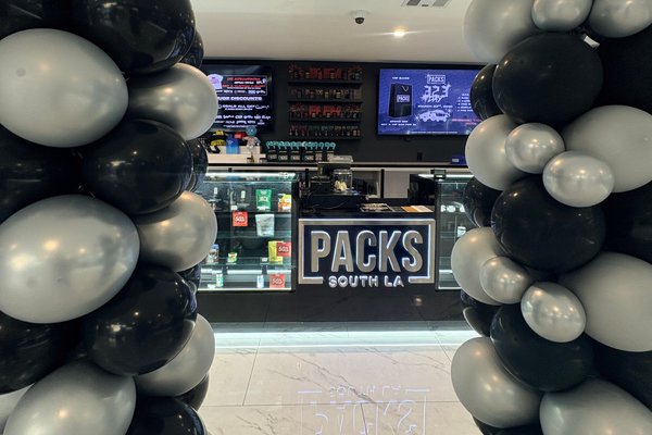 PACKS South LA dispensary counter with product displays, digital menus, and black and silver balloons.