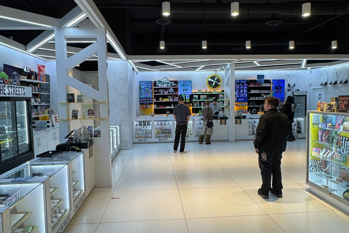 Interior of a well-lit store with display cases and shelves stocked with merchandise. Several people are browsing the products.